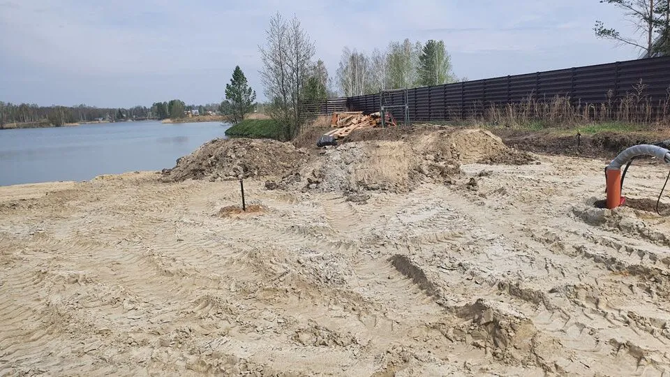 Песчаная стройплощадка с насыпью на берегу озера.
