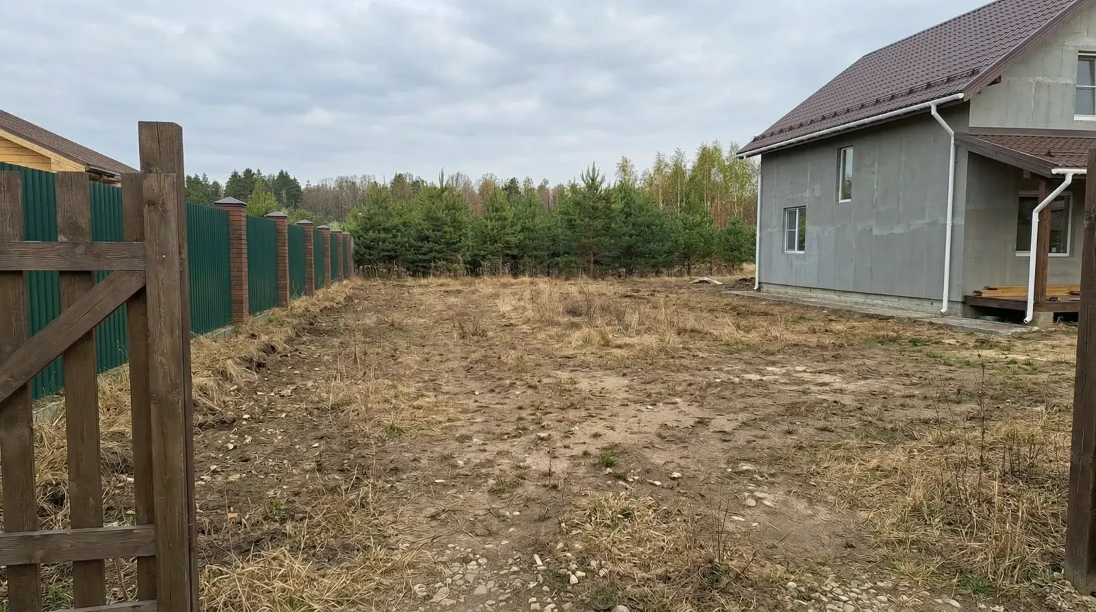 Недостроенный дом на неухоженном участке у соснового леса.