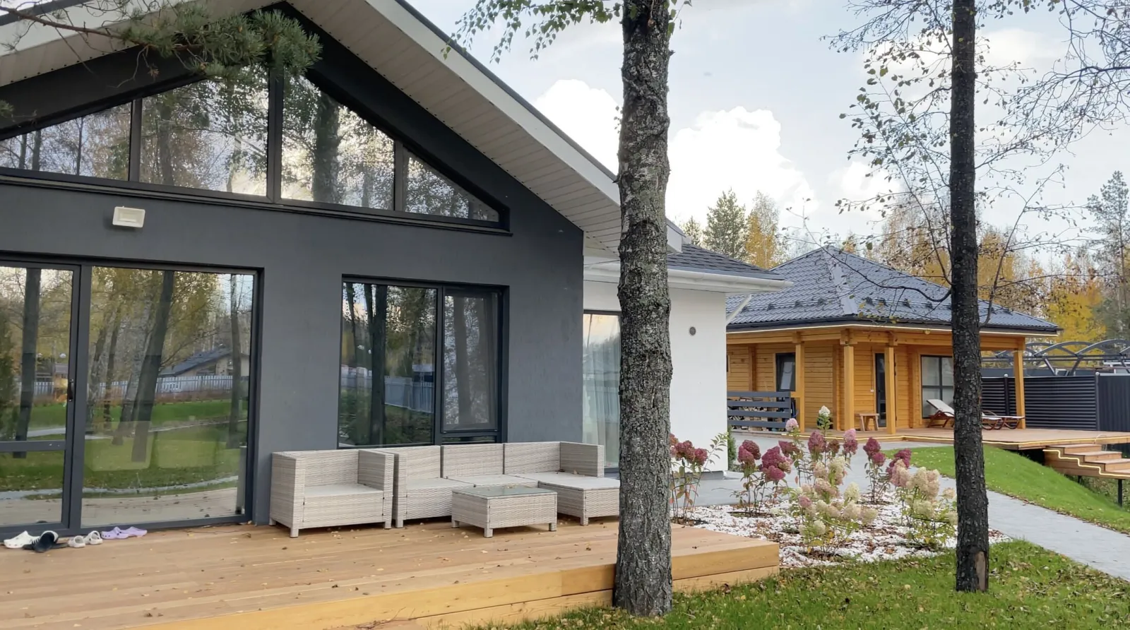 Современные загородные дома с террасами среди осенних деревьев.