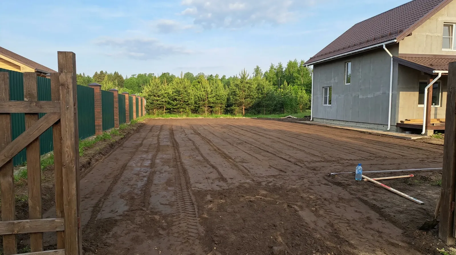 Расчищенный участок у загородного дома рядом с сосновым лесом.