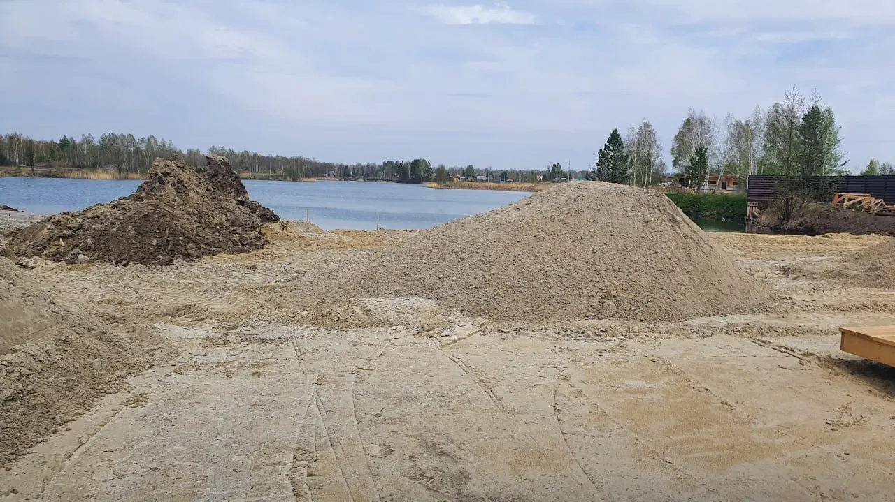 Песчаные насыпи на строительной площадке у озера.